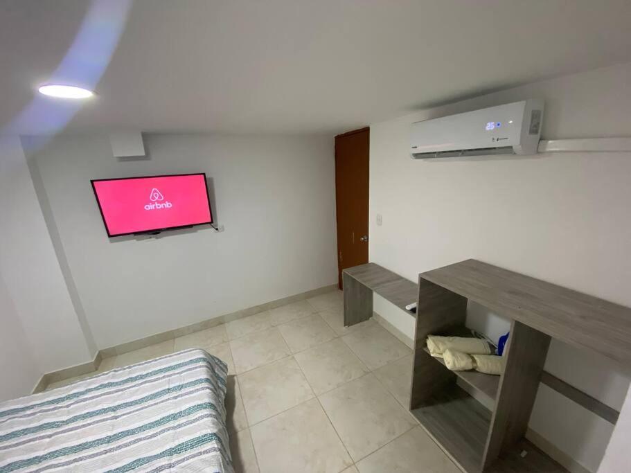 Zimmer mit einem Tisch und einem rosa Bildschirm an der Wand in der Unterkunft Apto en cucuta trapiches cerca a la Toyota in Villa del Rosario