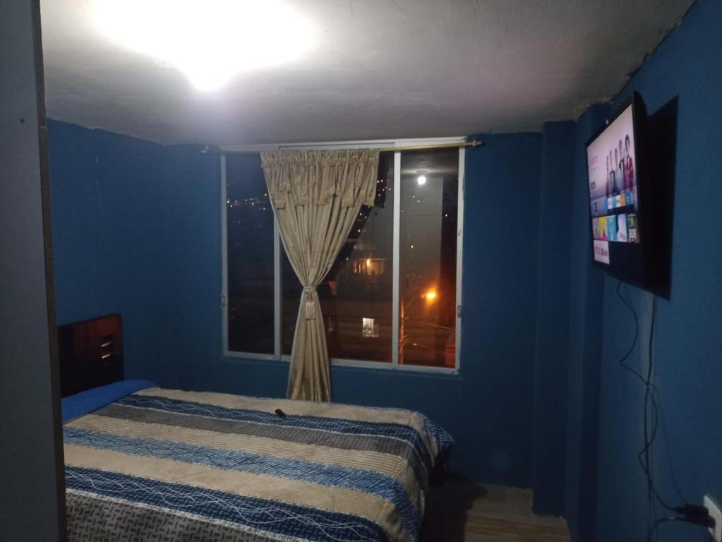 a blue bedroom with a bed and a window at Habitación Encantadora in Otavalo