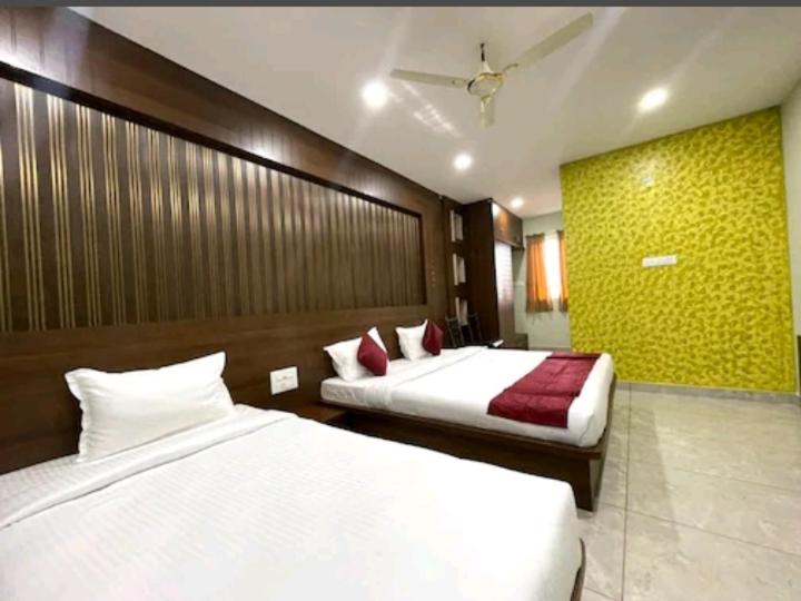 um quarto com 2 camas e uma parede amarela em Yashaswiny recidency em Mysore