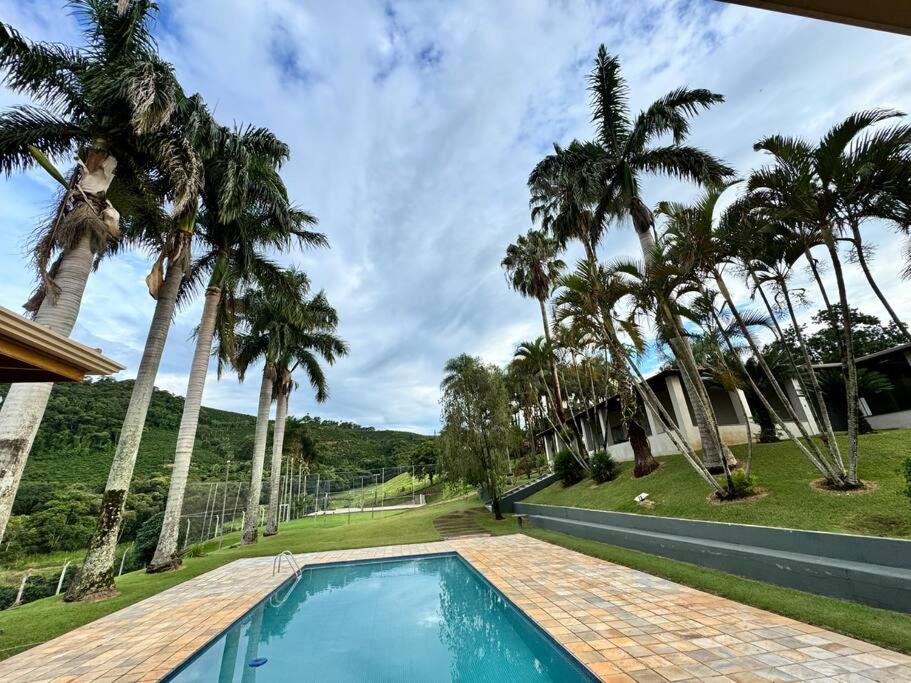 una piscina con palmeras frente a una casa en Casa de Campo Monte Sião, en Monte Sião