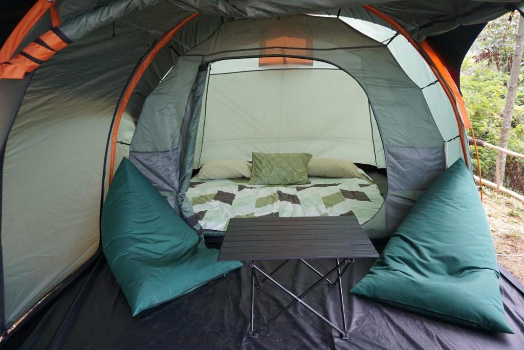 a tent with a bed and a table in it at ZOYA HILLS in Pondok Cipaseban