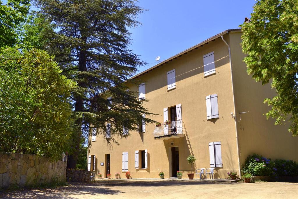 ein großes gelbes Gebäude mit einem Balkon und Bäumen in der Unterkunft Beau Séjour in Bocognano
