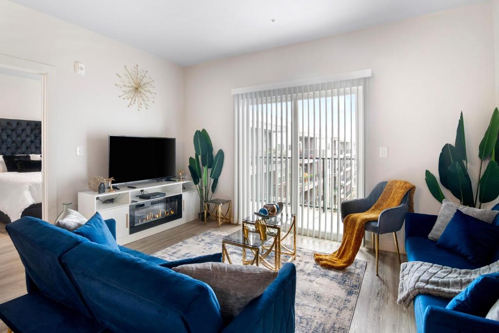 a living room with blue couches and a tv at BRAND NEW Luxurious, Spacious, Gated 2bd Apt in Houston