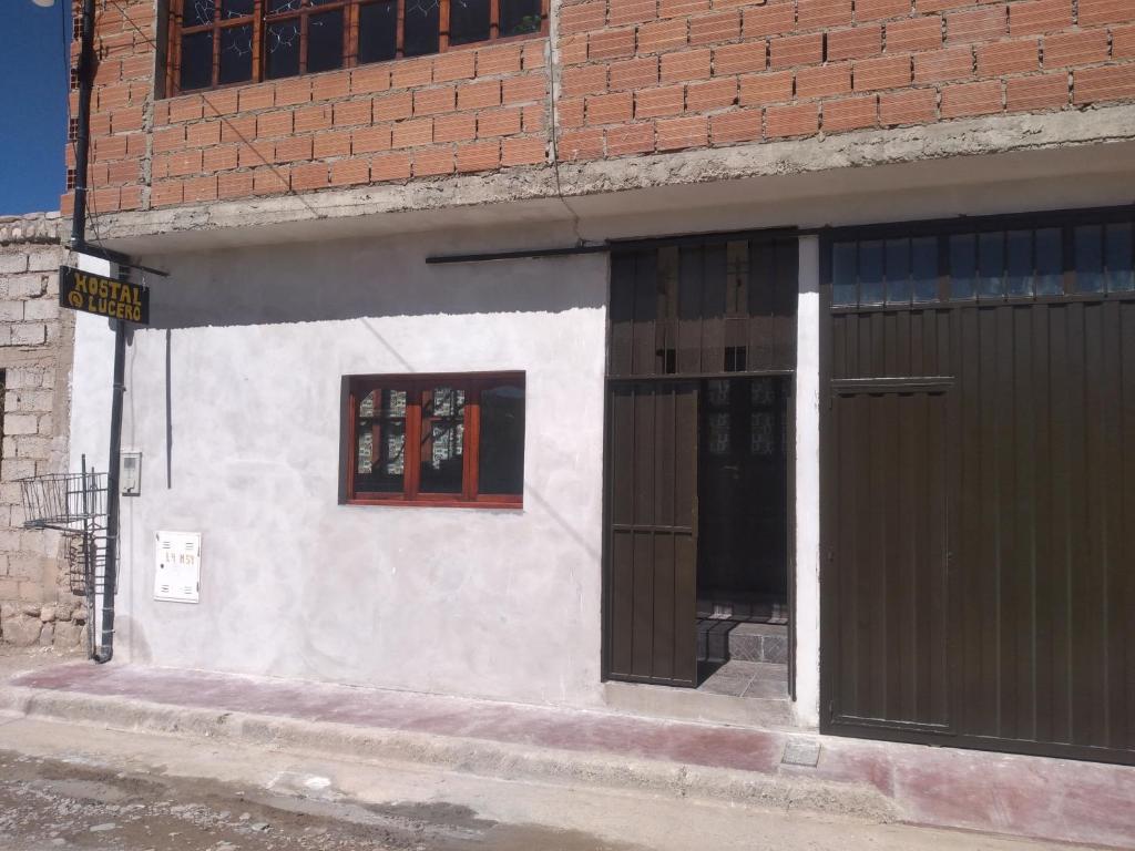 un edificio blanco con puertas negras en una calle en HOSTAL LUCERO en Humahuaca