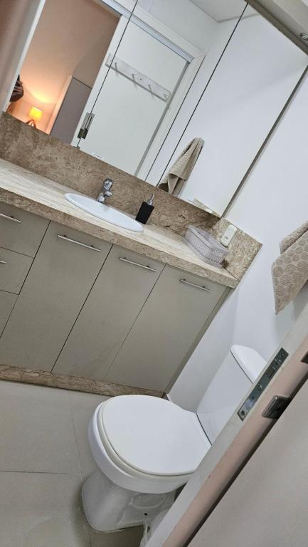 Łazienka z białą toaletą i umywalką w obiekcie Apt Confort - Suíte c/ hidro - 9 min da praia a pé w mieście Itapema