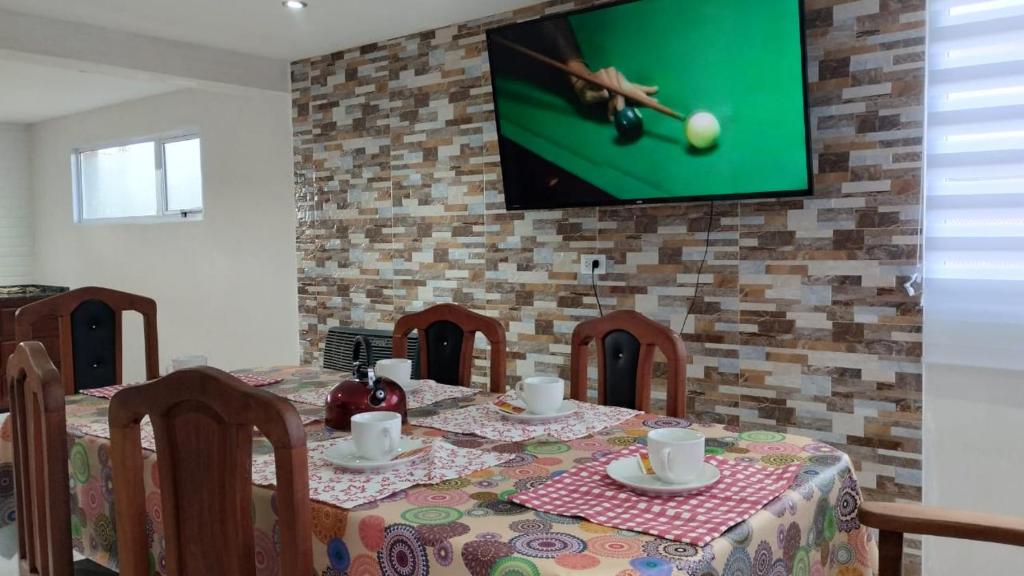 a table with chairs and a tv hanging on a brick wall at Jade 1840 casa completa in San Carlos de Bariloche
