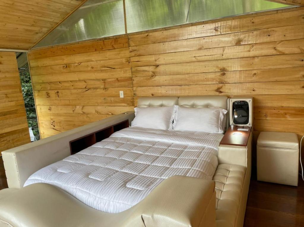 Cama en habitación con pared de madera en Villas del Rio Glamping en San Francisco