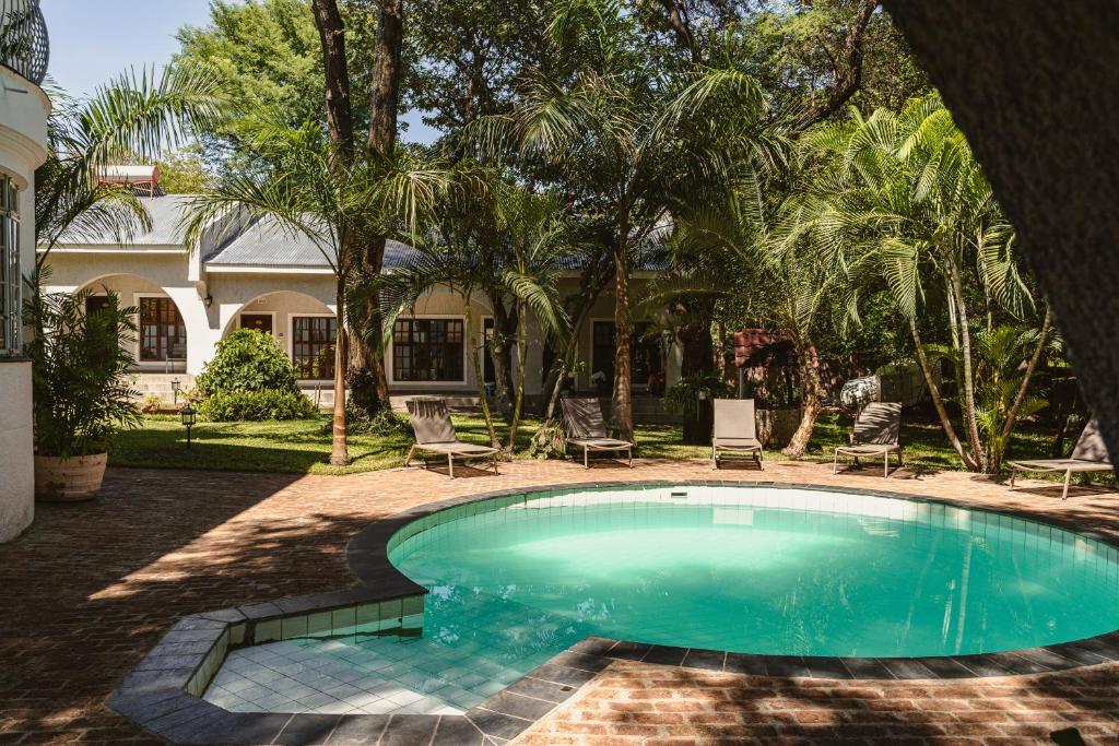 a swimming pool in a yard with chairs and a house at Jacaranda Lodge in Victoria Falls
