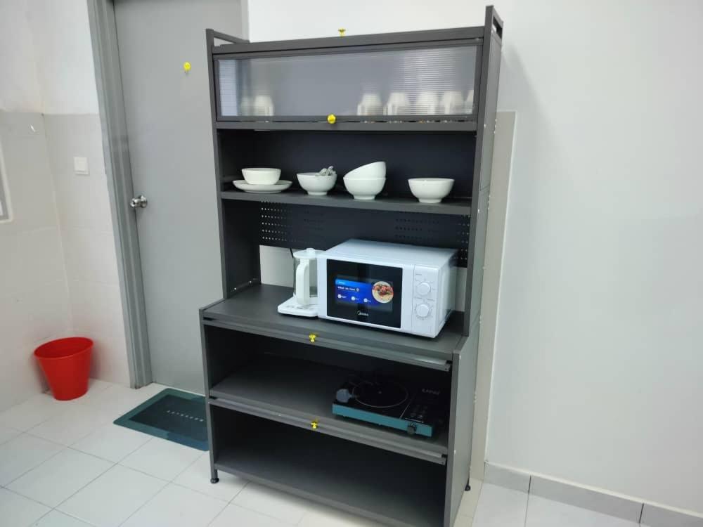 a shelf with a microwave and bowls on it at Jalan Sena Indahpura Landed House in Kulai