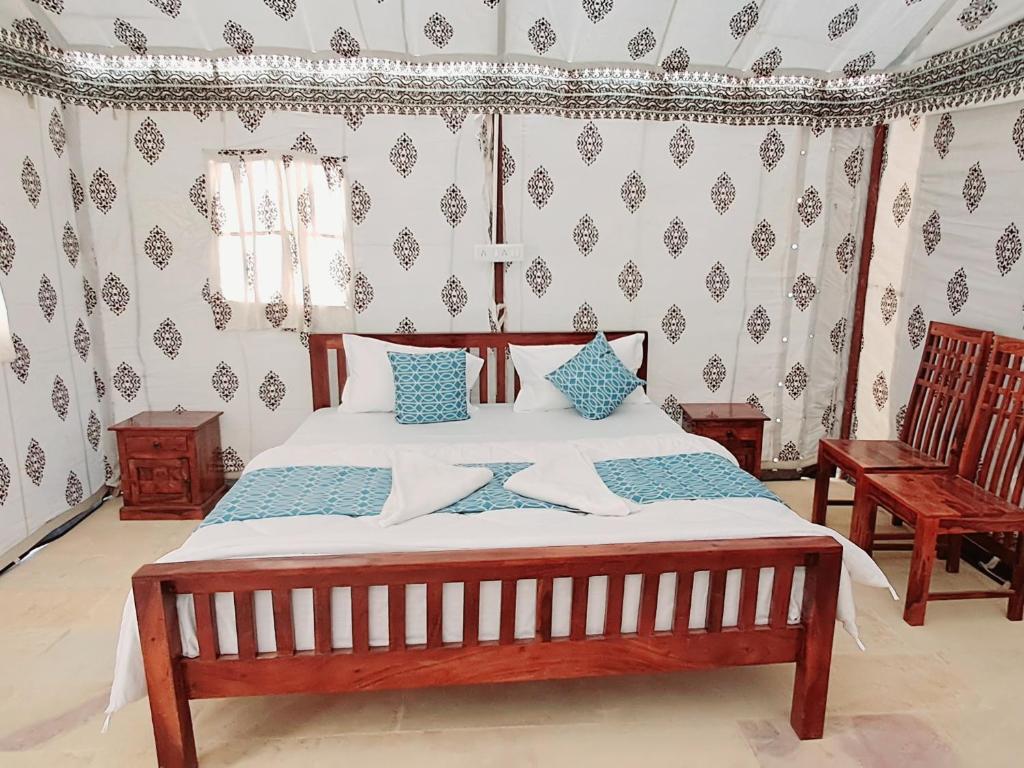 a bedroom with a large bed with two chairs at Robin Desert Safari Camp in Jaisalmer