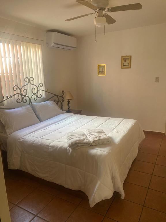 a bedroom with a bed with white sheets and a fan at Depa a unos minutos de consulado! in Hermosillo