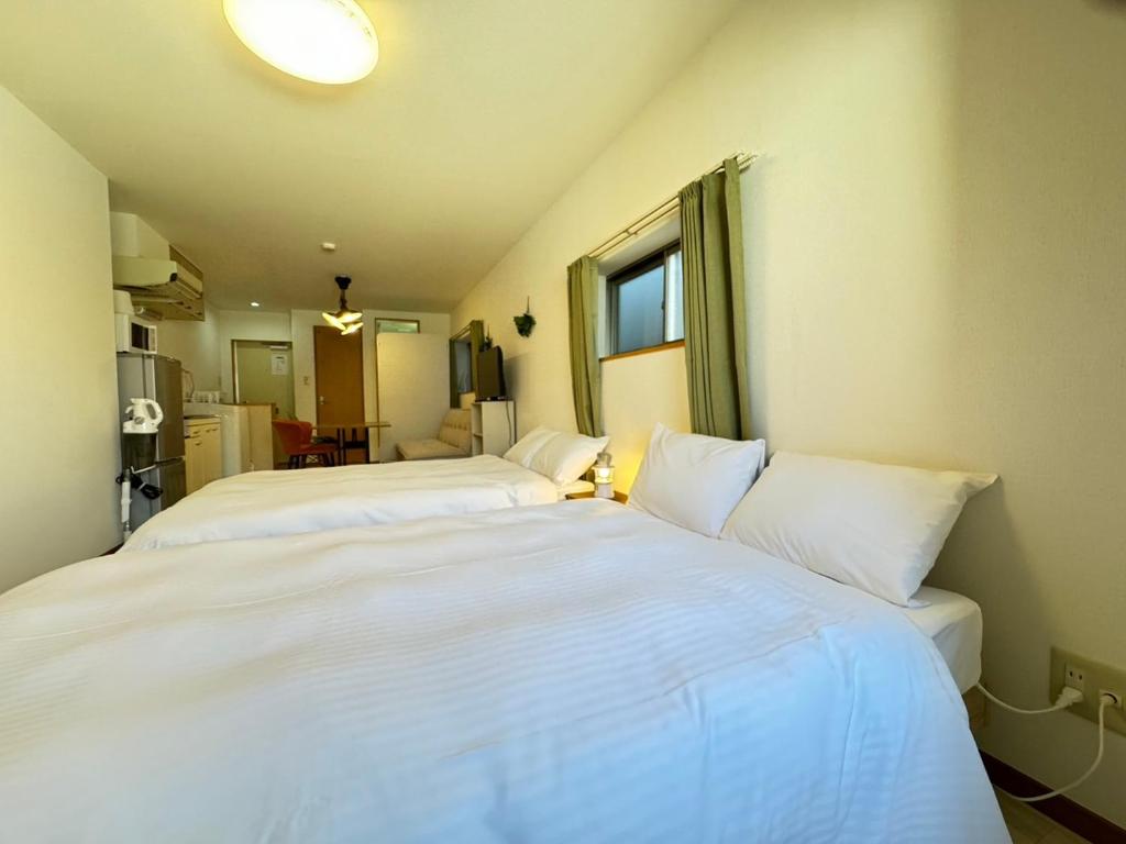 1 dormitorio con 2 camas y almohadas blancas en マルチステイ大阪天保山22 en Osaka