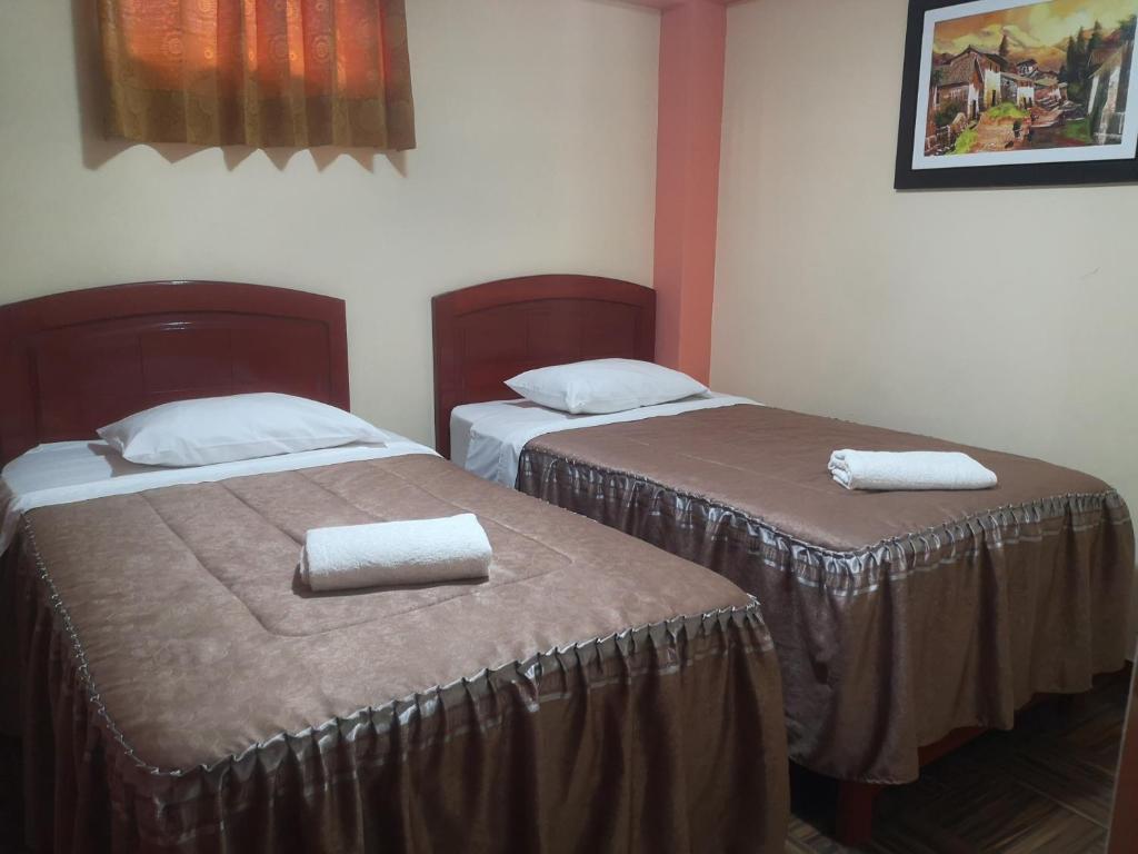2 Betten in einem Hotelzimmer mit Handtüchern darauf in der Unterkunft Hotel lucero real in Tacna