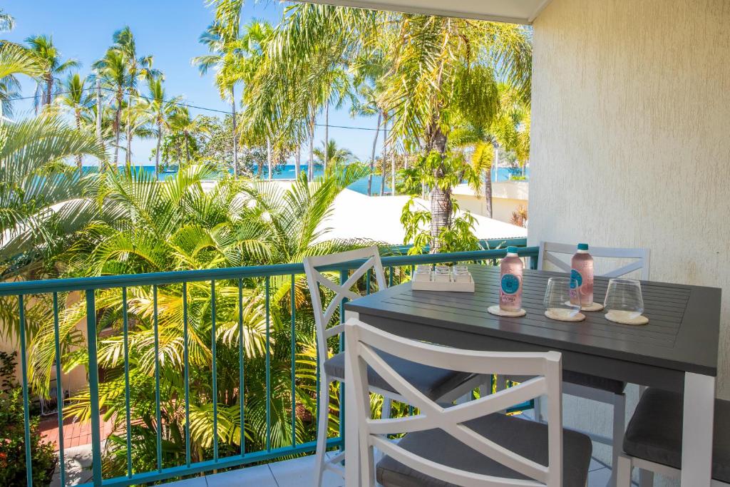 a table and chairs on a balcony with palm trees at Unit 10 Sails on Horseshoe in Horseshoe Bay