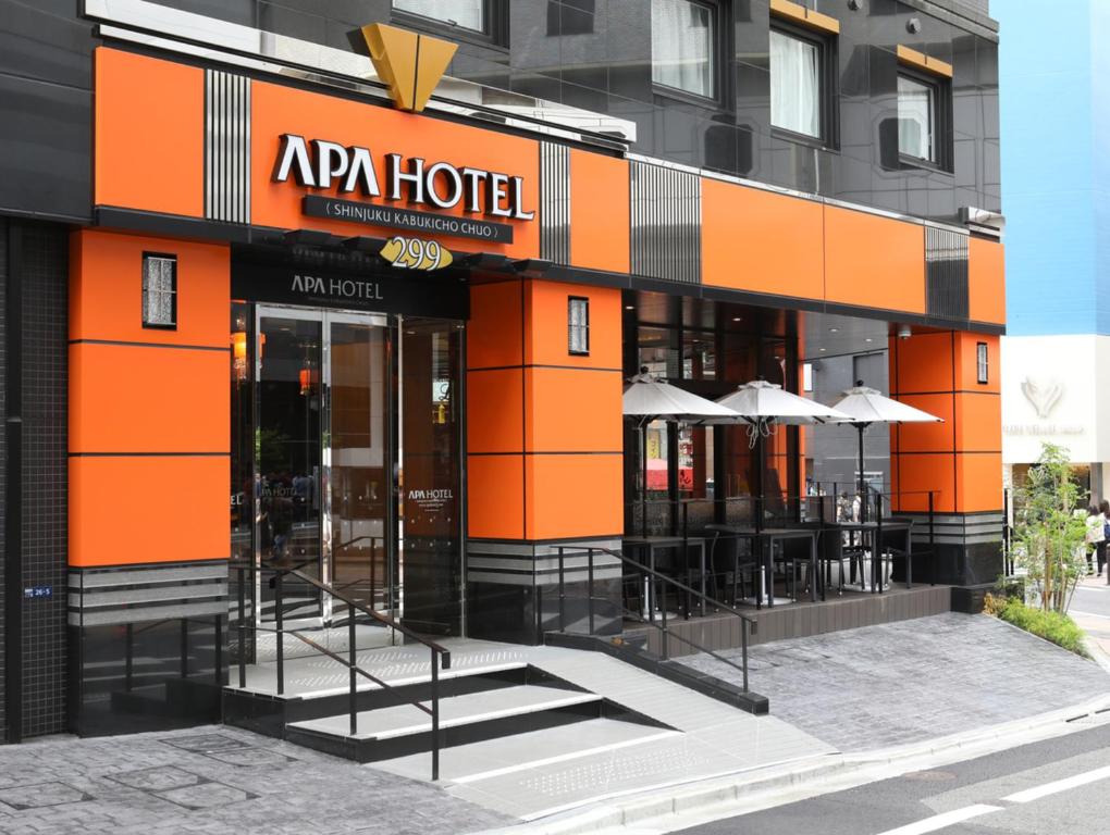 een oranje hotel met tafels en parasols buiten bij APA Hotel Shinjuku Kabukicho Chuo in Tokyo