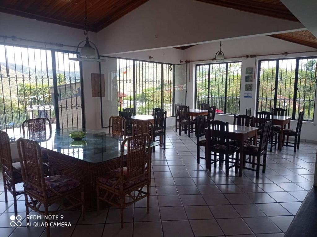 uma sala de jantar com mesas, cadeiras e janelas em Finca Anapoima Tranquila em La Mesa