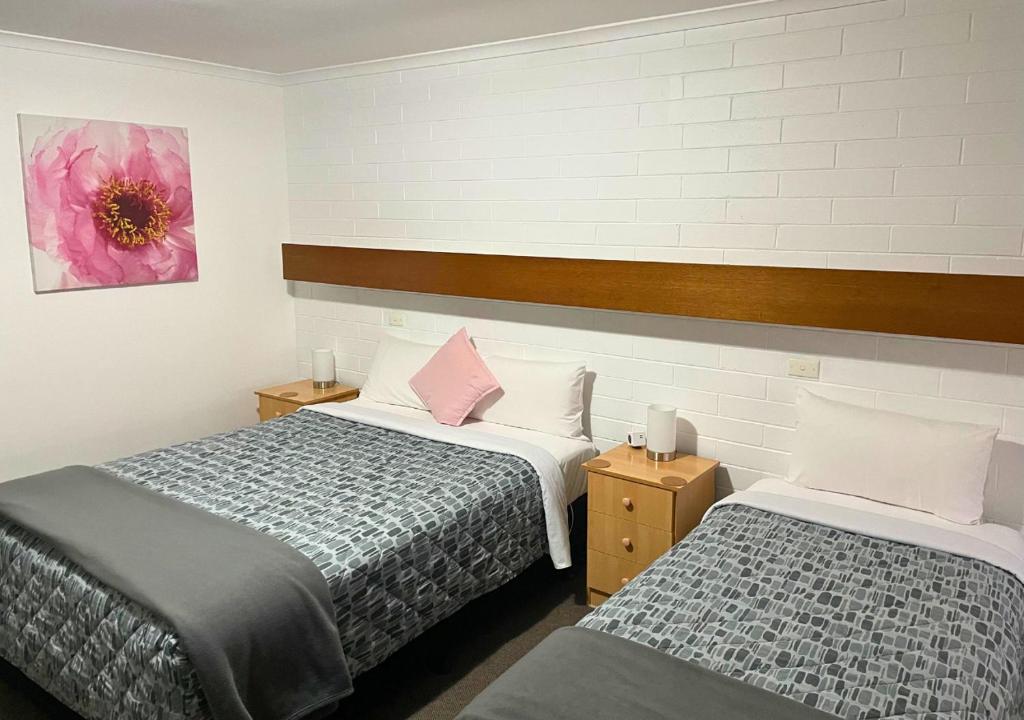 ein Schlafzimmer mit 2 Betten und einer rosa Blume an der Wand in der Unterkunft Orana Motor Inn in Mildura