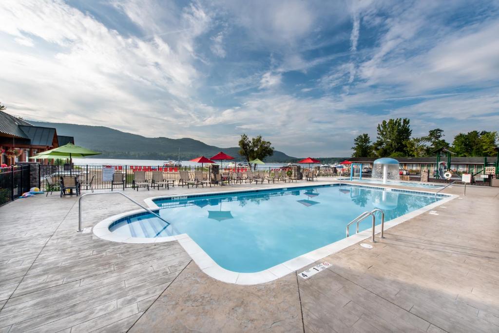 een zwembad in een resort met tafels en stoelen bij Scotty's Lakeside Resort in Lake George