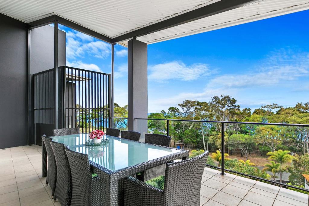 an outdoor dining room with a glass table and chairs at The Bay Apartments in Hervey Bay
