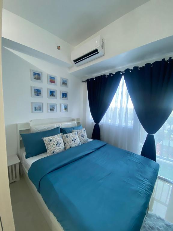 a blue bed in a bedroom with a window at Serene Skyline Escape Las Pinas in Manila