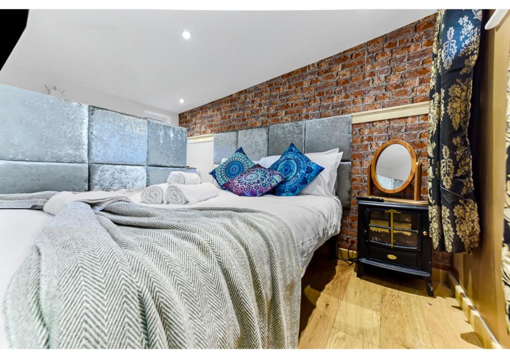 a bedroom with a large bed and a brick wall at Charming Log Cabin with Hot Tub & Grill in London