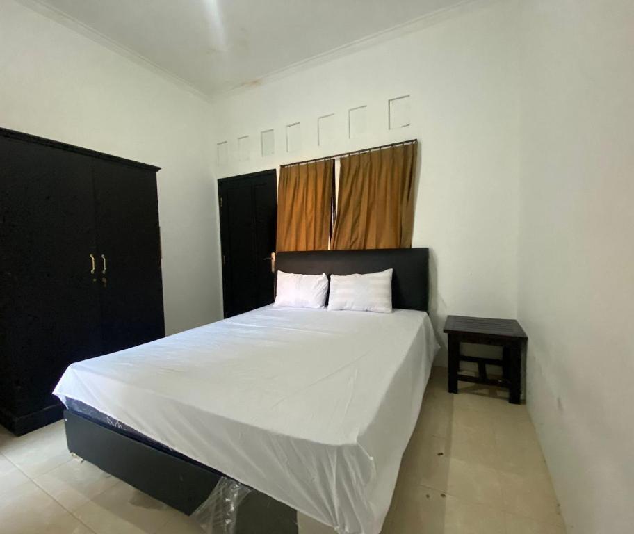 a bedroom with a bed with white sheets and a window at OYO Life 93255 Kosan Teratai Jaya in Tanjung