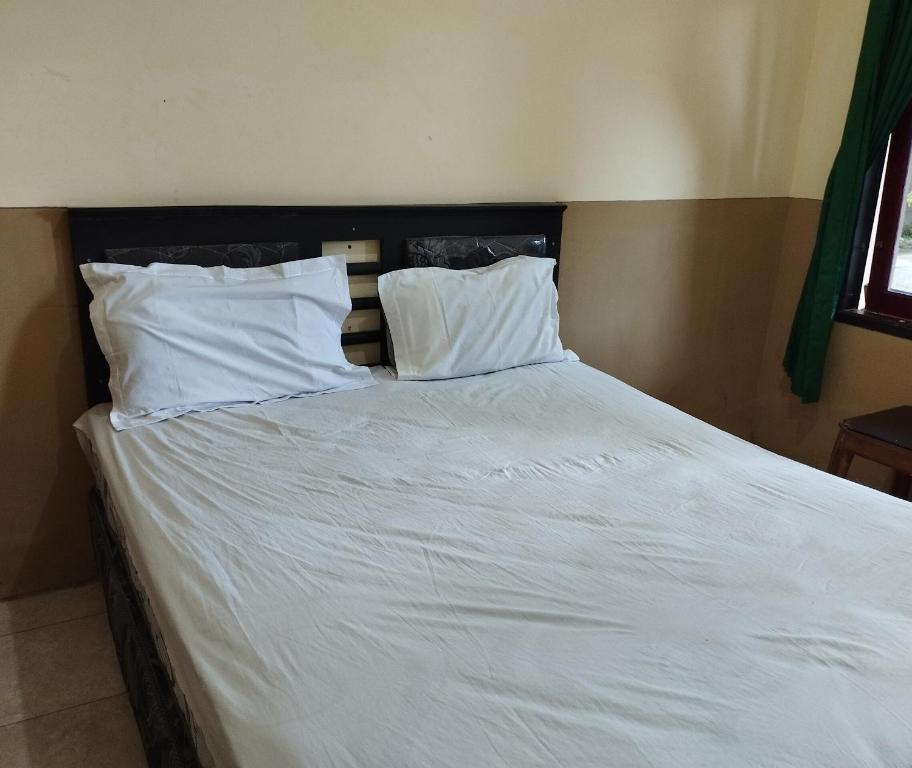 a bed with white sheets and pillows in a bedroom at OYO Life 93265 Kos Cendana Seruni Raya in Mataram