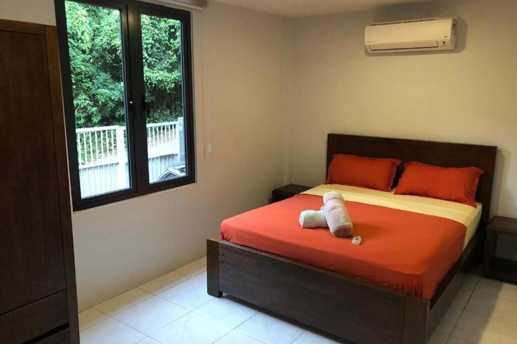 a bedroom with a bed with red sheets and a window at 2 bedrooms Apartment in Pantai Cenang