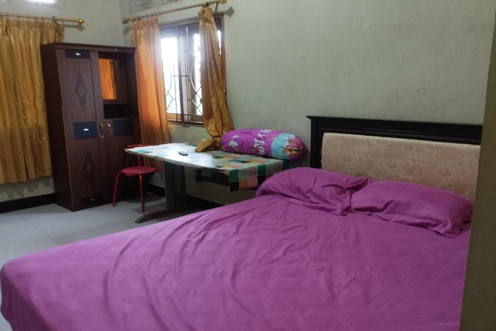 1 dormitorio con cama morada y escritorio en OYO Life 93403 Penginapan Adinda, en Tjakranegara