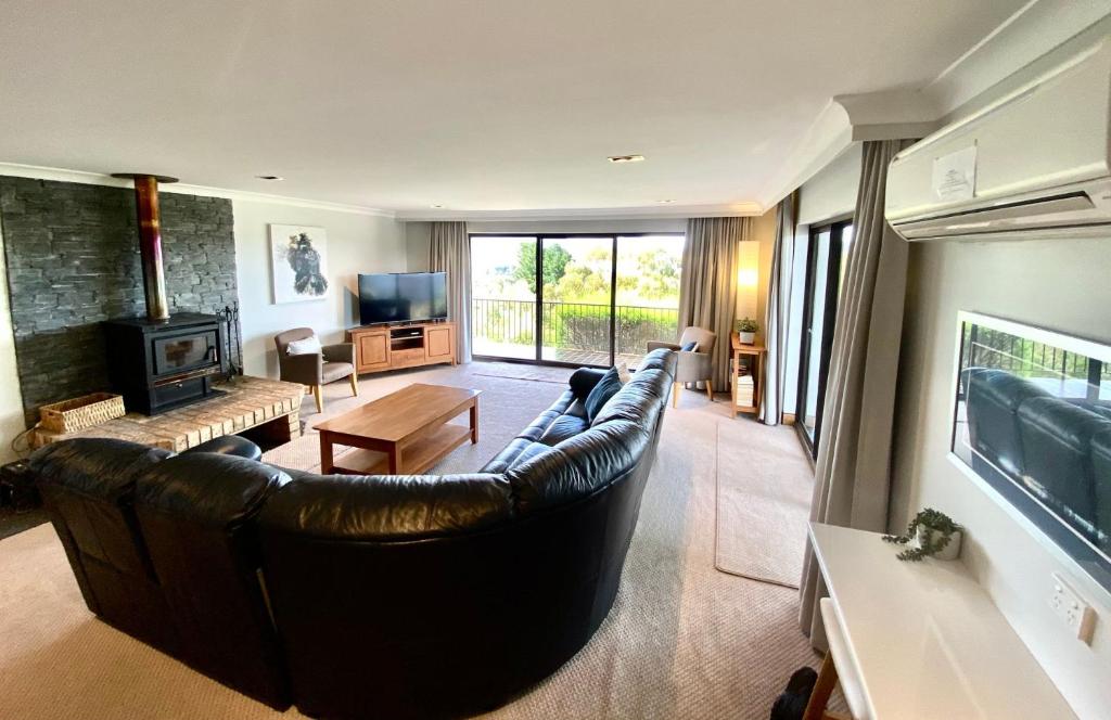 a living room with a leather couch and a fireplace at Aviemore 4 14 Cobbodah Street in Jindabyne