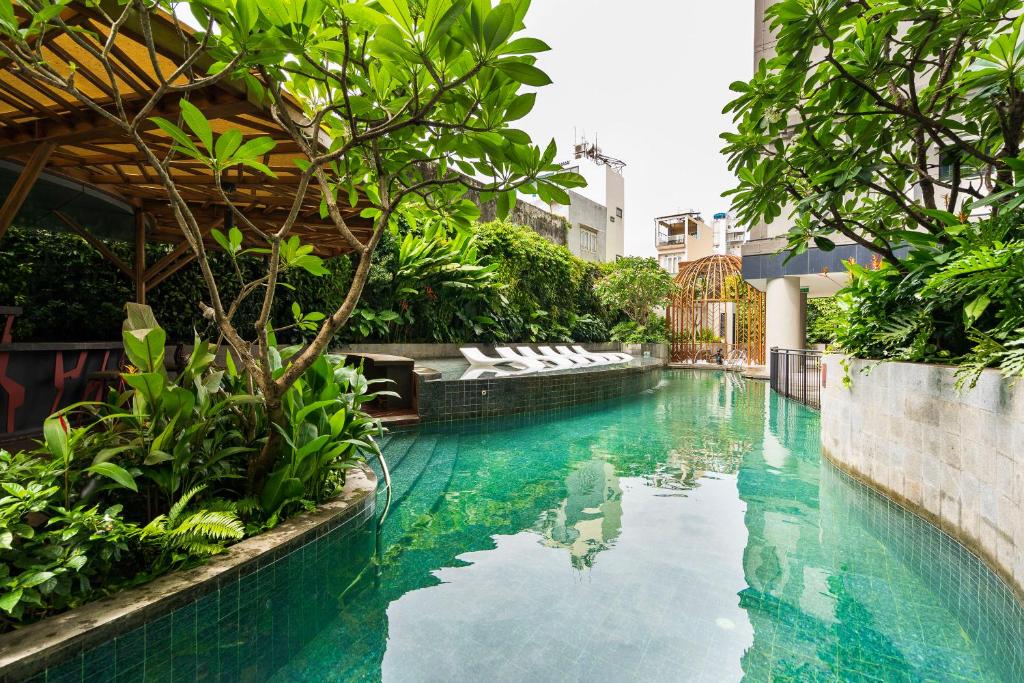 una piscina con agua azul y plantas verdes en Zenity 3BR Condo: Luxury and Comfort in Quận 1, en Ho Chi Minh