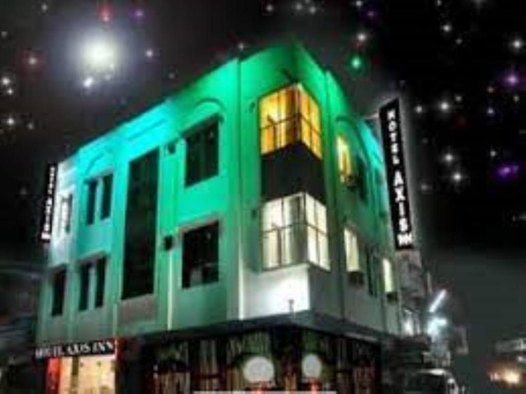 un edificio verde con una luz encendida por la noche en HOTEL AXIS INN, Amritsar, en Amritsar