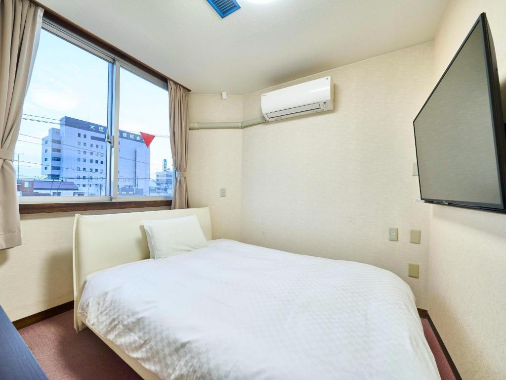 a bedroom with a bed and a large window at Okasan Hotel - Vacation STAY 77664v in Ogaki