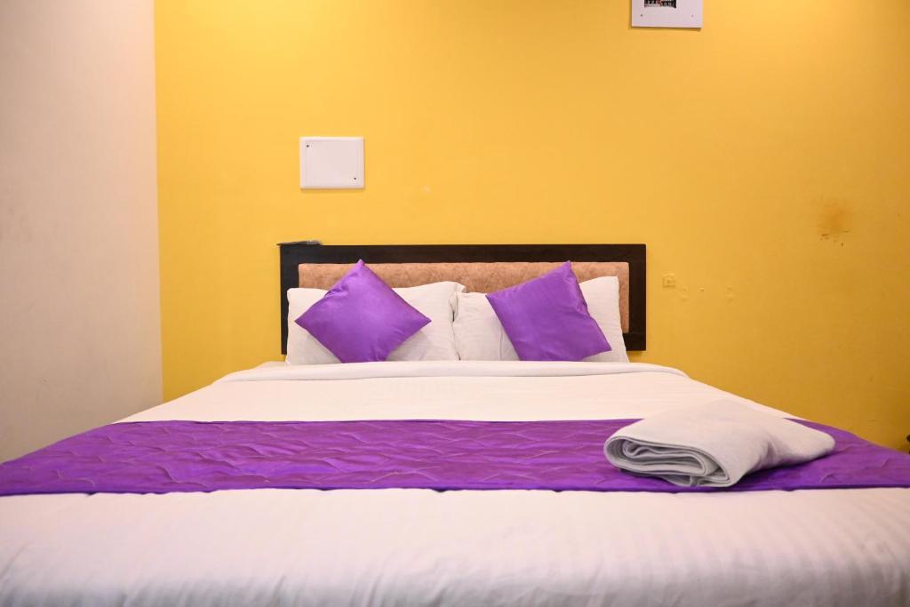 Cama grande con sábanas y almohadas moradas y blancas en Hotel SY Comforts en Bangalore