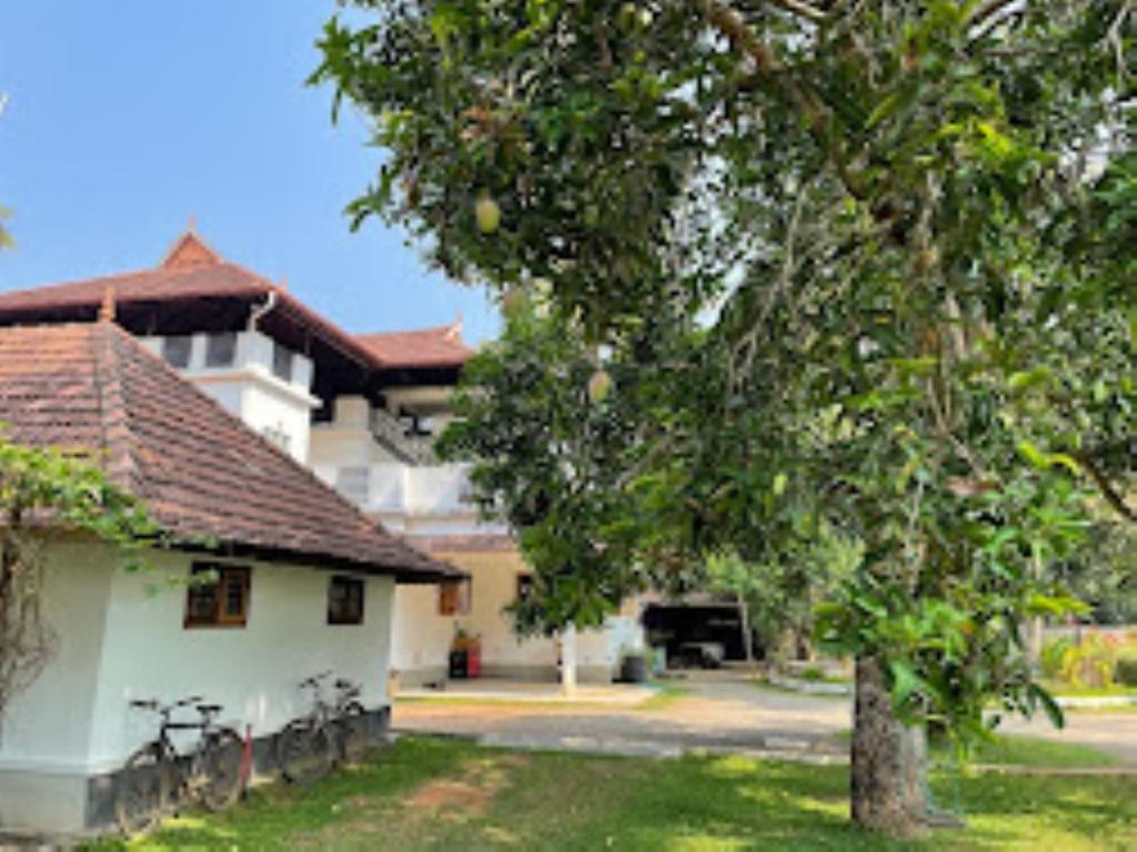 a house with a tree in front of a building at THE PAMBA HERITAGE VILLA Nedumudy in Champakulam