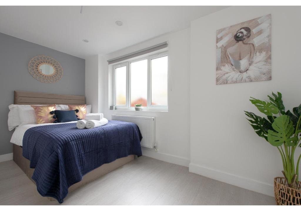 una camera da letto con un letto con una coperta blu e una finestra di Splendid and Comfy 1 bedroom apartment a Londra