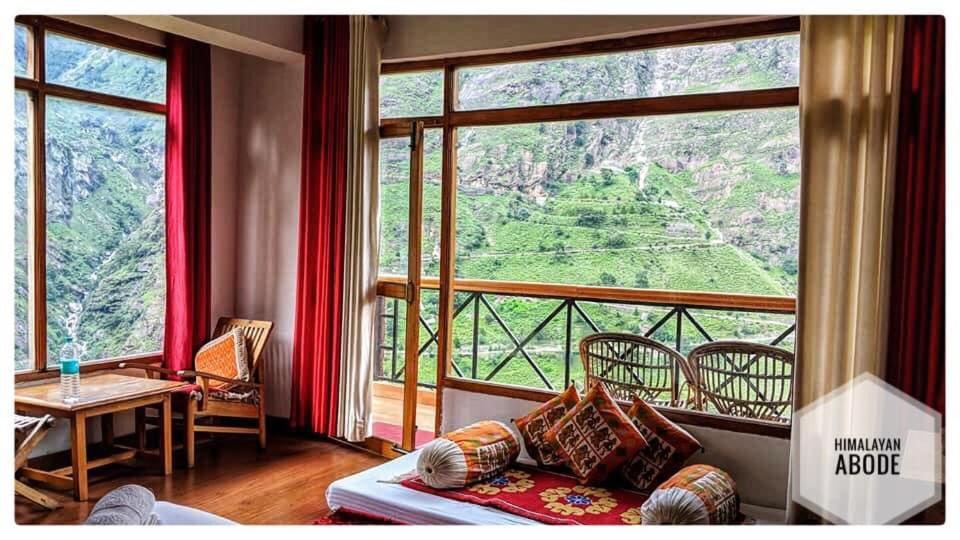 a living room with a couch and a large window at Himalayan Abode Joshimath in Joshīmath