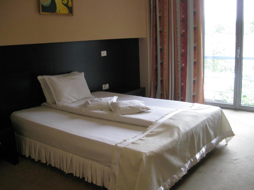 a bed with white sheets and pillows in a bedroom at Hotel Delpack in Timişoara
