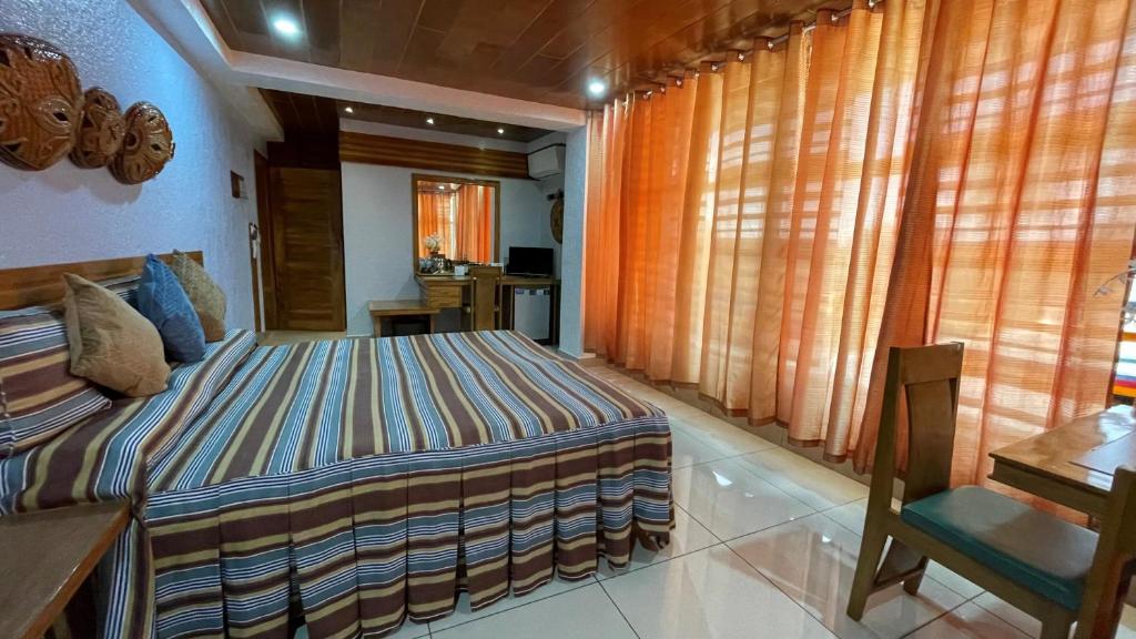 Schlafzimmer mit einem Bett, einem Schreibtisch und Fenstern in der Unterkunft CITI HOTEL in Hilongos