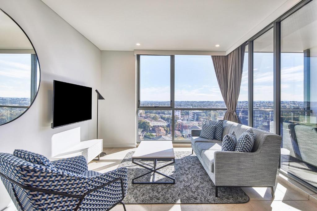 a living room with a couch and chairs and windows at Meriton Suites Liverpool in Liverpool