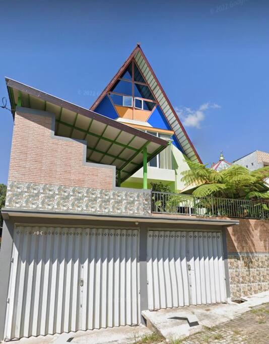 a house with a white fence and a building at Villa Songgokerto Batu in Songgoriti