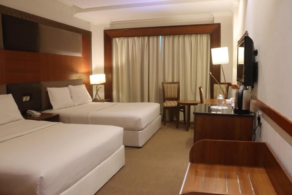 a hotel room with two beds and a desk at GSS Avenue Hotel Ex Delmon Hotel in Dubai