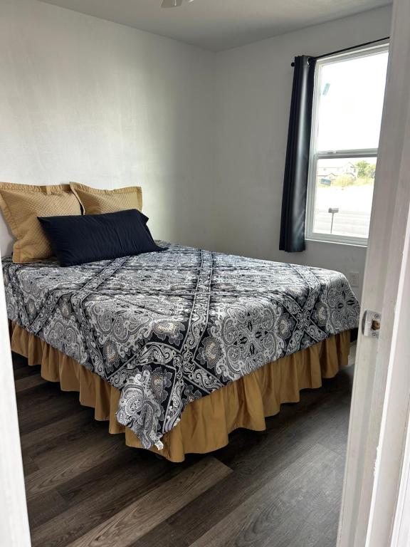 1 dormitorio con 1 cama con manta y ventana en Near Red Mountain park en Mesa