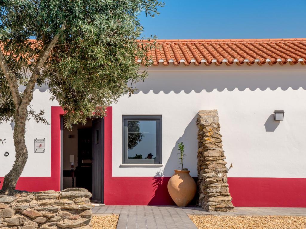 una casa roja y blanca con una planta delante en Fontes Bárbaras Enoturismo en Entradas