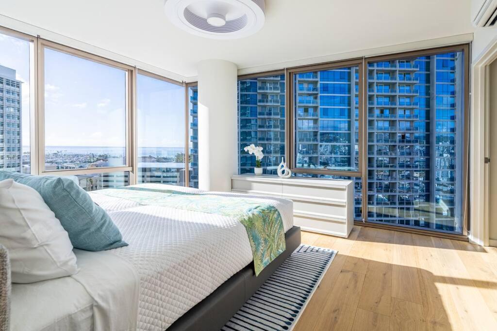 a bedroom with a bed and large windows at Brand New! Luxurious Sky Ala Moana 2 Bed 2 Bath in Honolulu