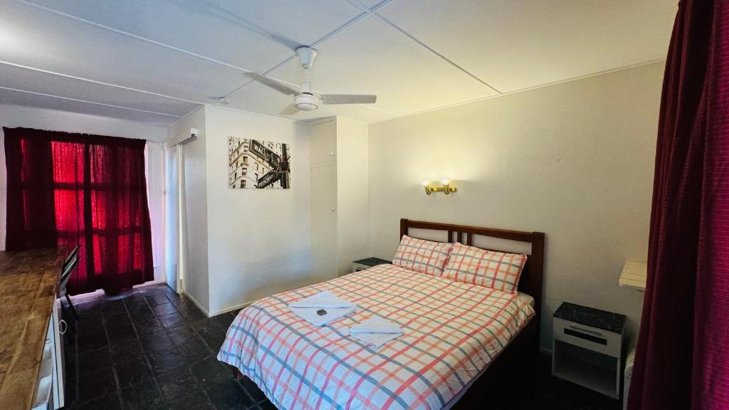 a small bedroom with a bed and a ceiling fan at Colosseum Creek Motel in Colosseum