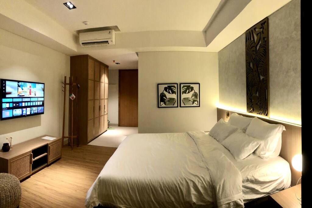 a bedroom with a white bed and a flat screen tv at Cozy Minimalist Apartment Lavaya N511 in Nusa Dua