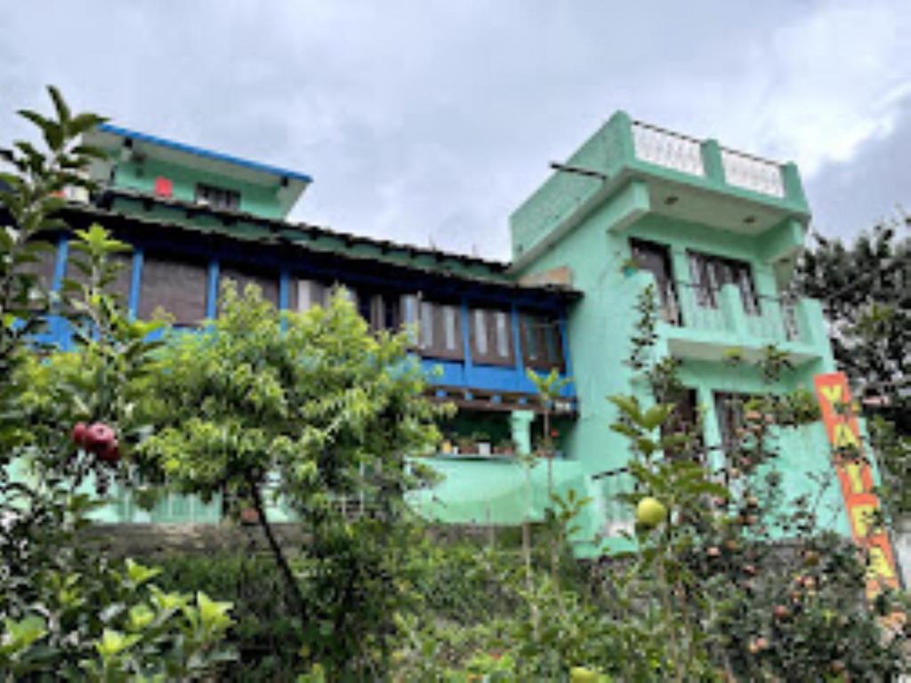 a green building with trees in front of it at YATRA HOMESTAY Joshimath in Joshīmath