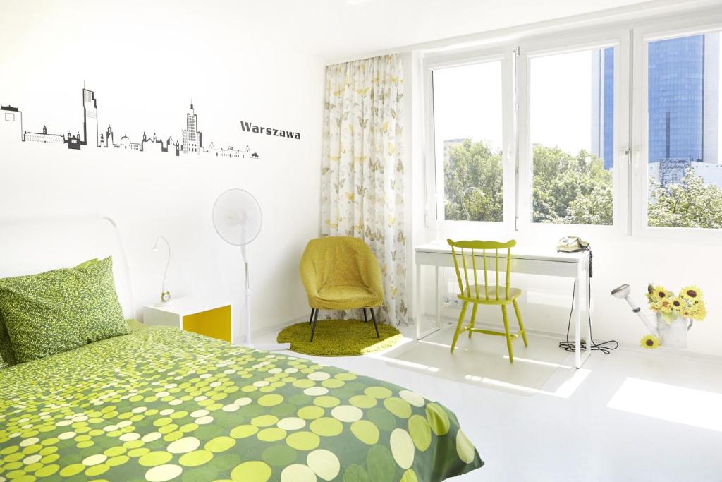 Schlafzimmer mit einem Bett, einem Schreibtisch und Fenstern in der Unterkunft Lovely Sunny Flat in City Center in Warschau