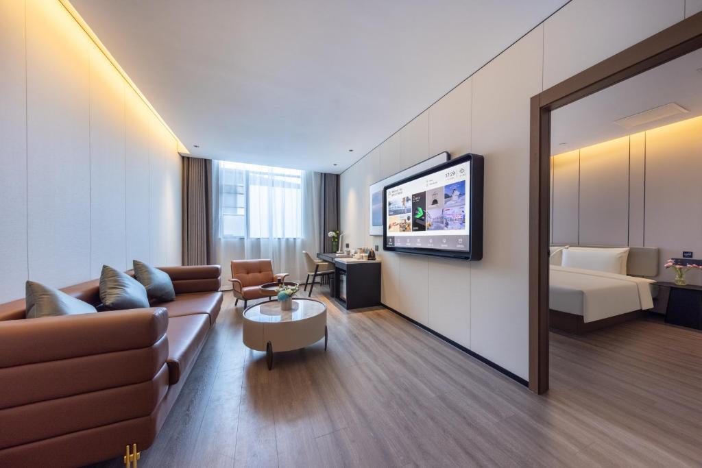 a living room with a couch and a bed and a television at Atour Hotel Guangzhou Panyu Wanbo CBD Hanxi Changlong in Guangzhou